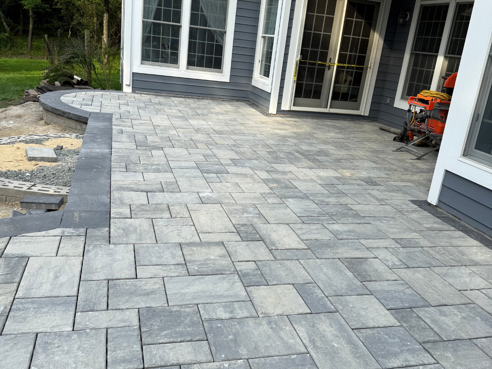 Patio with gray pavers and curved edge, showcasing integrated design elements for functionality and aesthetics, enhancing outdoor space for residential landscaping.