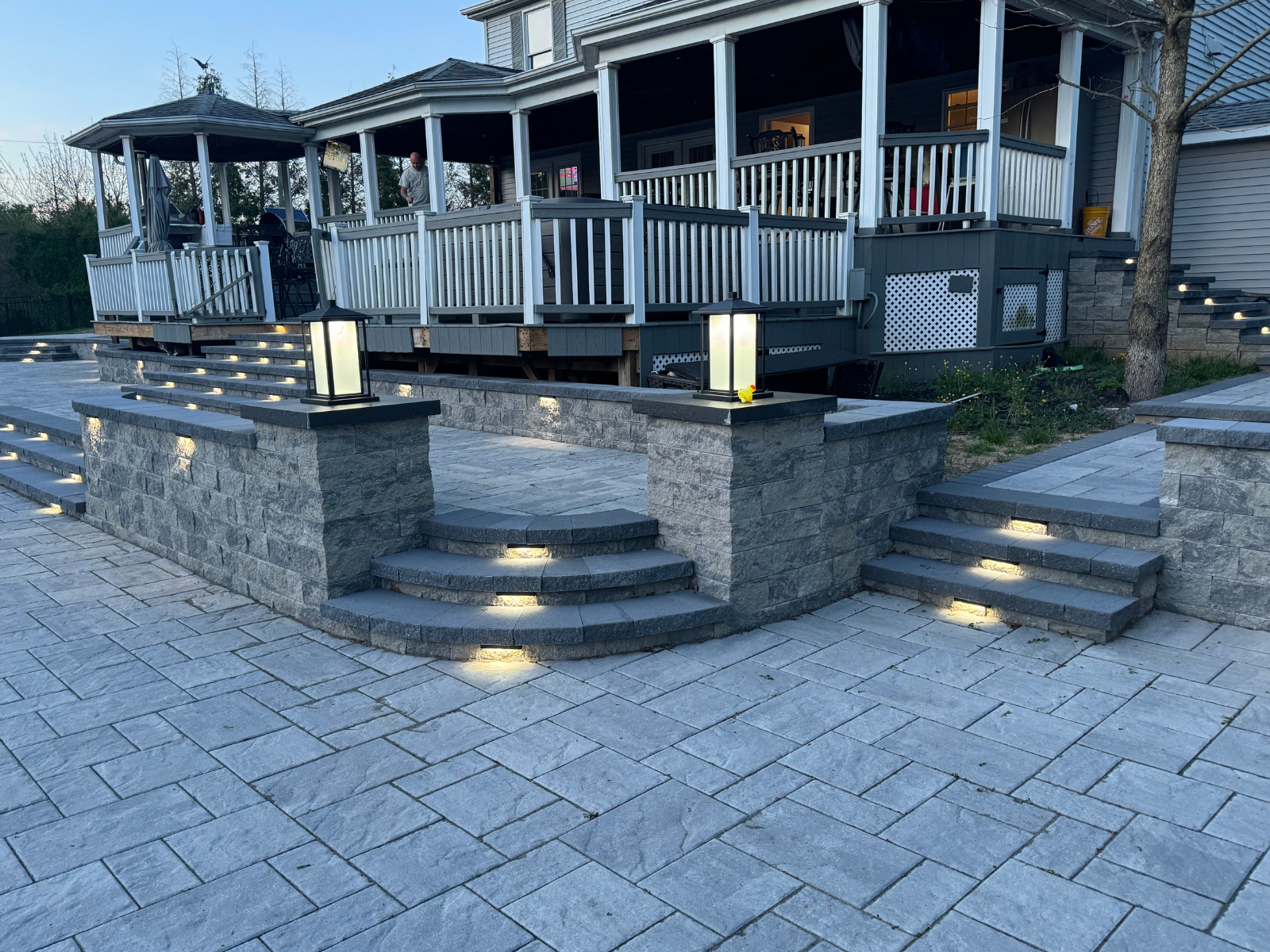 Outdoor living space featuring stone steps, integrated lighting, and a gazebo, highlighting functional design elements for summer shade and rain protection.