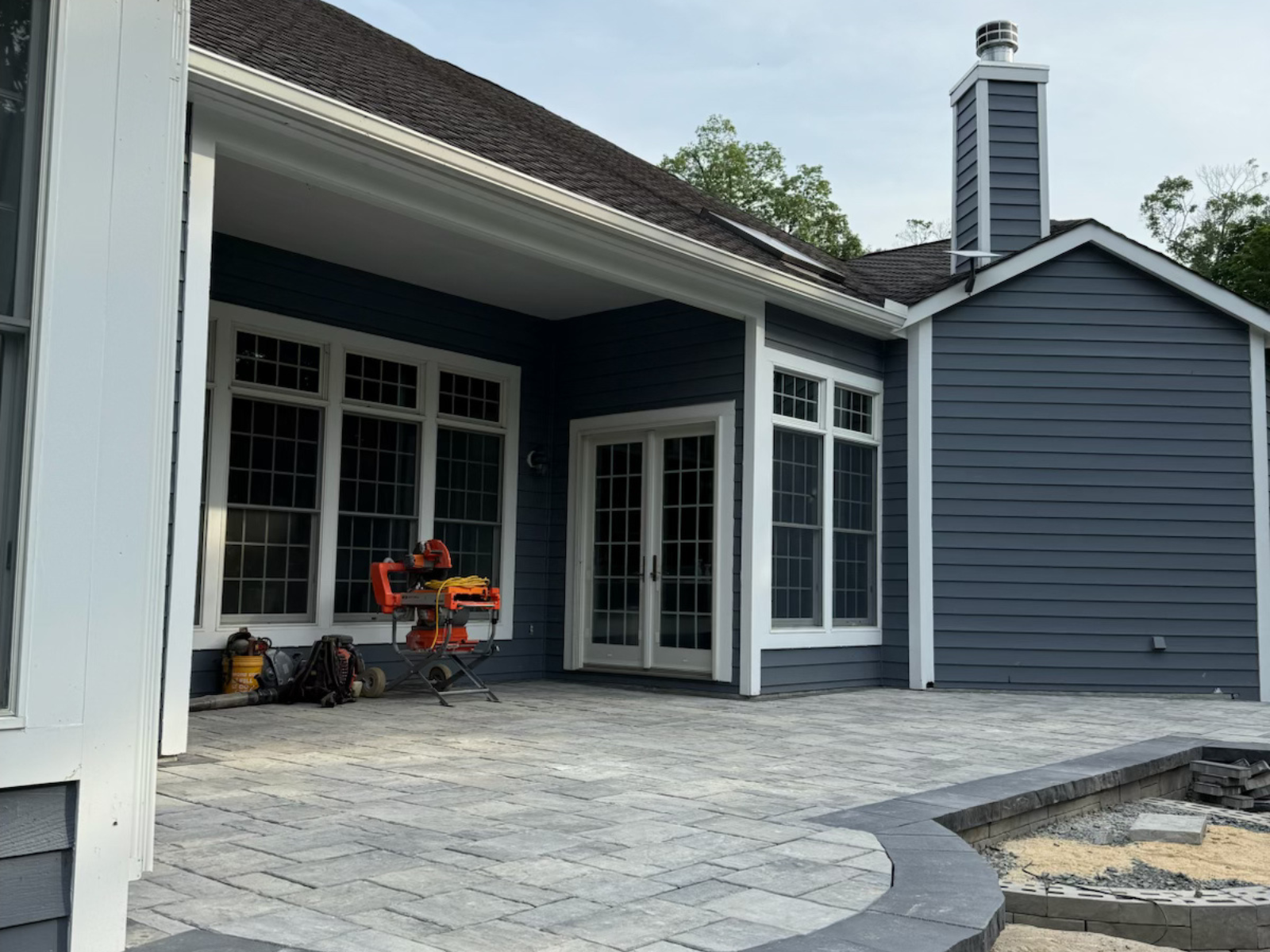 Patio installation featuring paver stones, integrated planters, and built-in seating, showcasing a modern outdoor living space designed by Urban Landscapes.