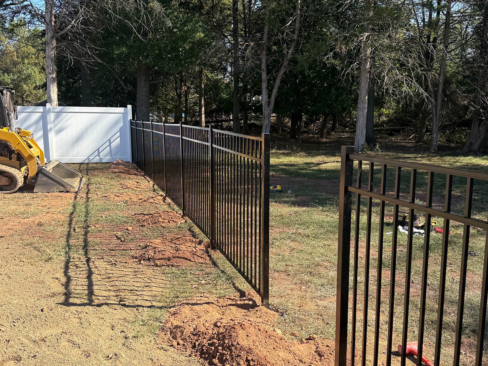 Black metal fencing installation alongside a white vinyl fence in a residential yard, showcasing a professional fencing project by Urban Landscaper in Princeton, NJ.