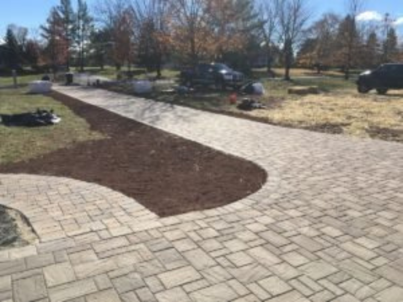 Paver walkway installation with curved design, freshly mulched area, and landscaping in progress, showcasing custom hardscaping solutions for outdoor spaces in Princeton.