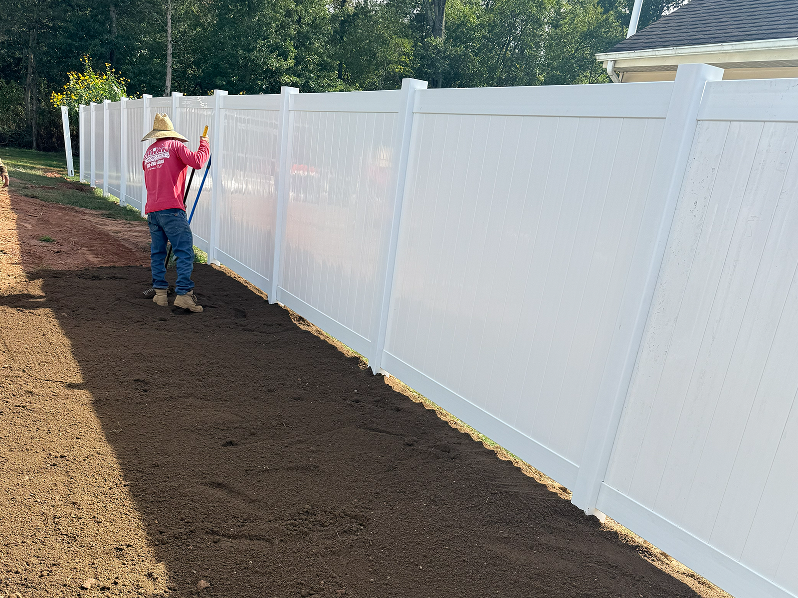 Worker installing vinyl fencing in a landscaped area, showcasing low-maintenance durability and aesthetic appeal for homeowners in Princeton, NJ.